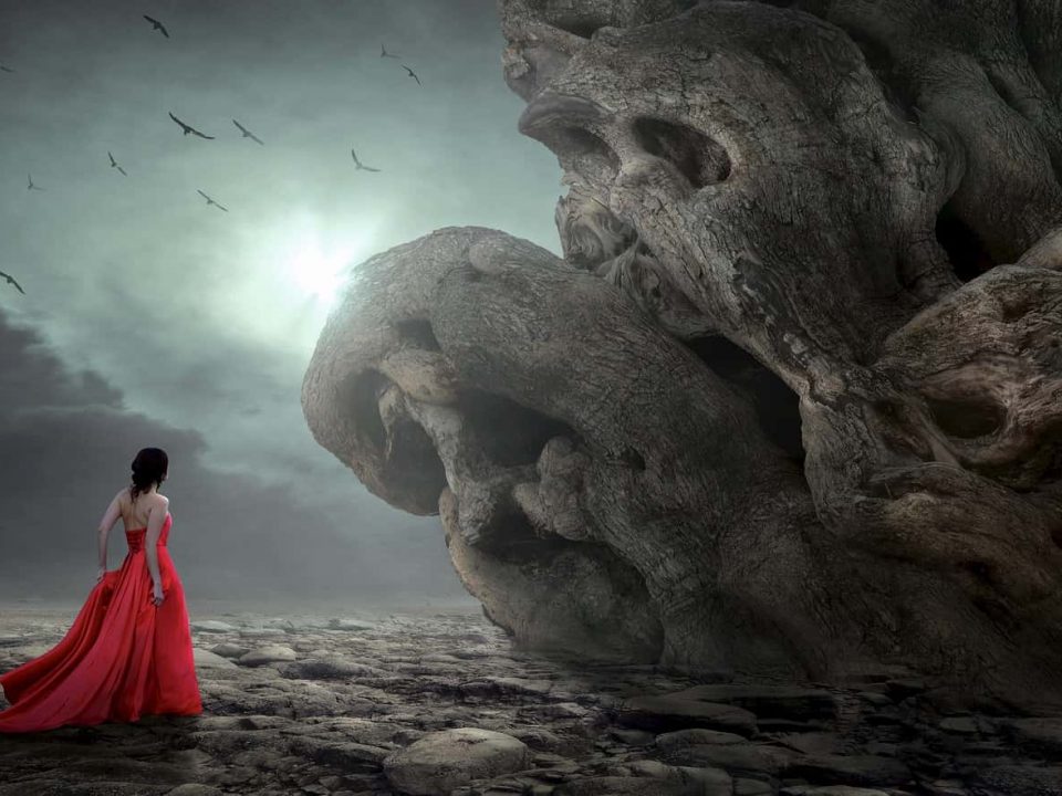 Une femme portant une robe de soirée rouge fait face à des rochers semblables à des cranes de mort dans un paysage sombre